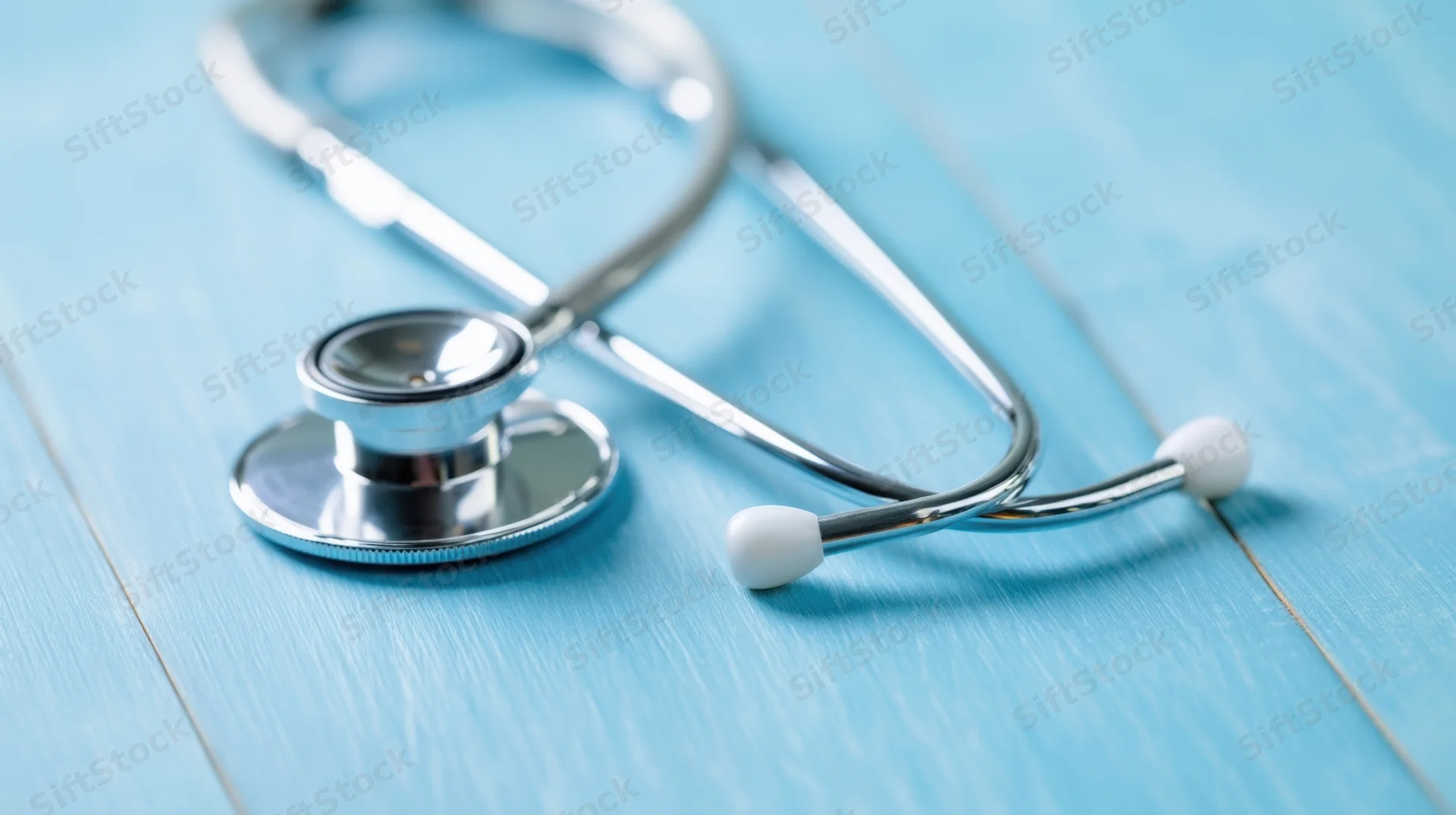 Silver stethoscope resting on a blue wooden surface