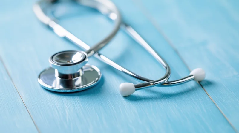 Silver stethoscope resting on a blue wooden surface