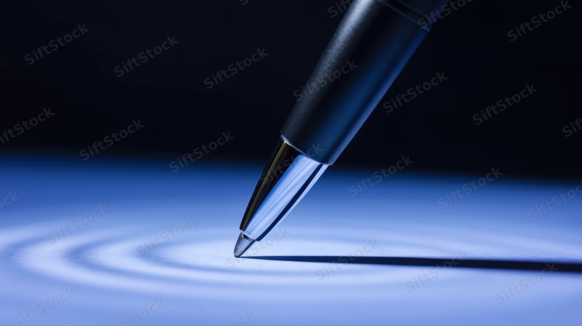 Sleek pen tip hovering over a blue surface with concentric light ripples