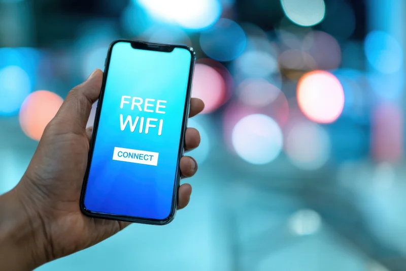 Hand holding smartphone with free wifi connect screen in city night setting