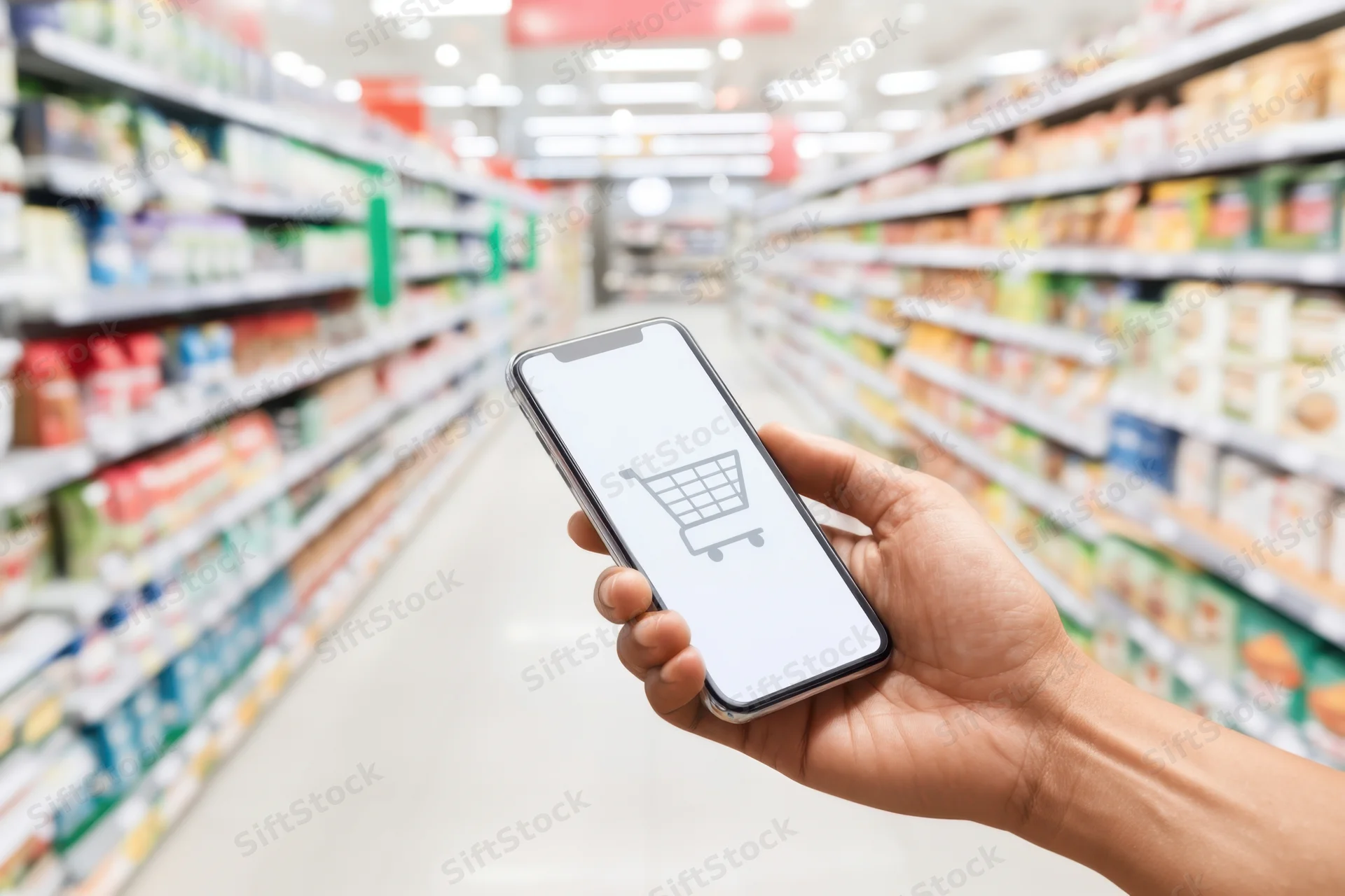 Hand holding smartphone with shopping cart icon in supermarket aisle