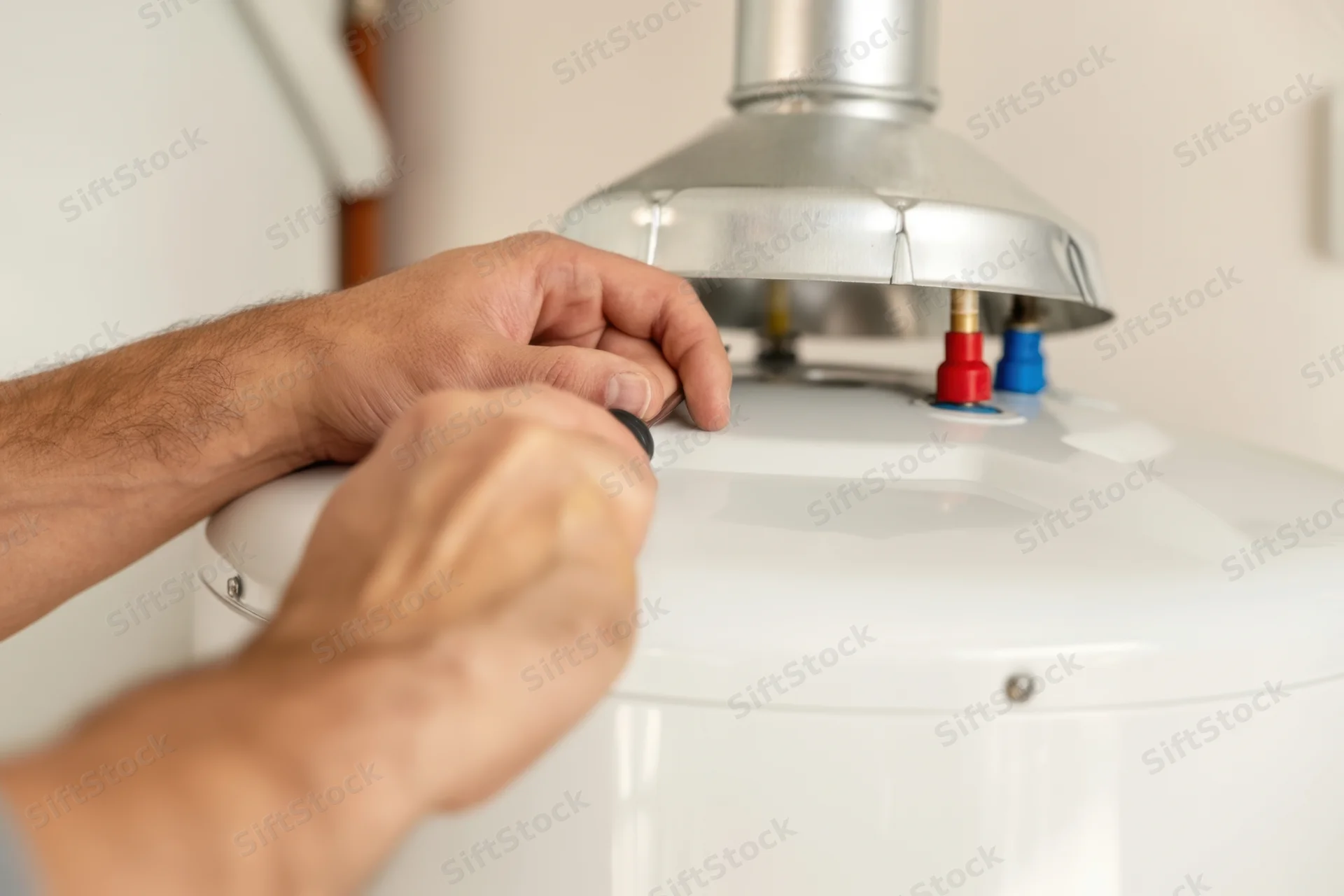 Technician adjusting valve on white water heater in residential setting