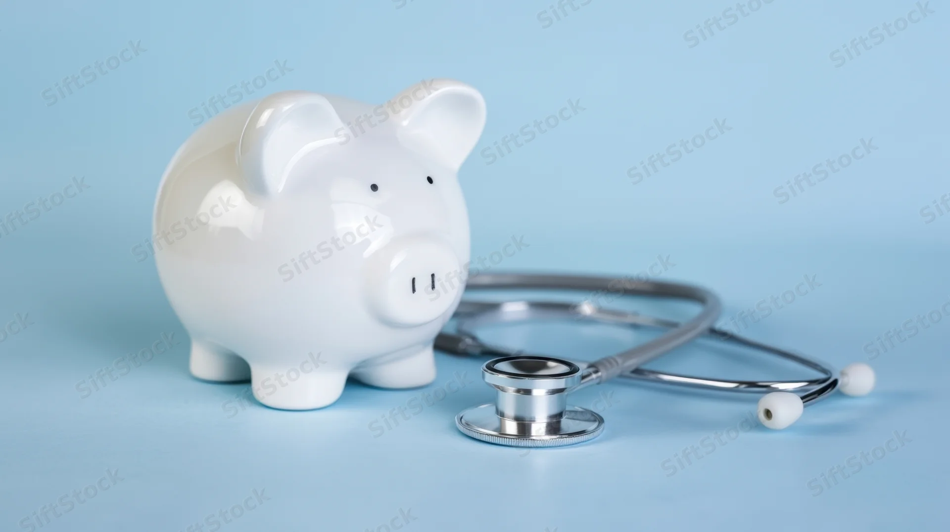 White ceramic piggybank beside a stethoscope on a blue surface