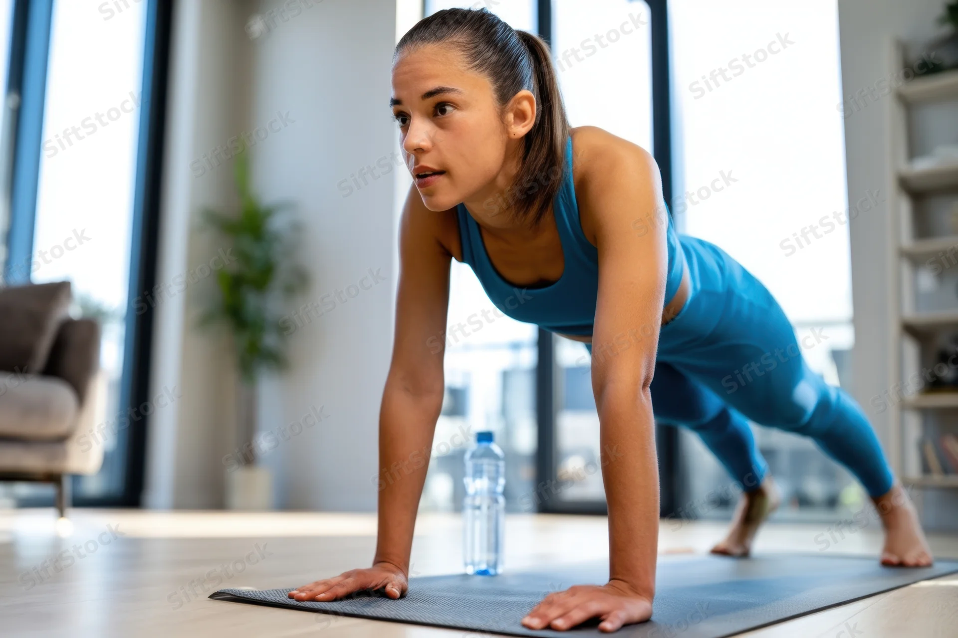 Woman doing pushup on yoga mat in living room