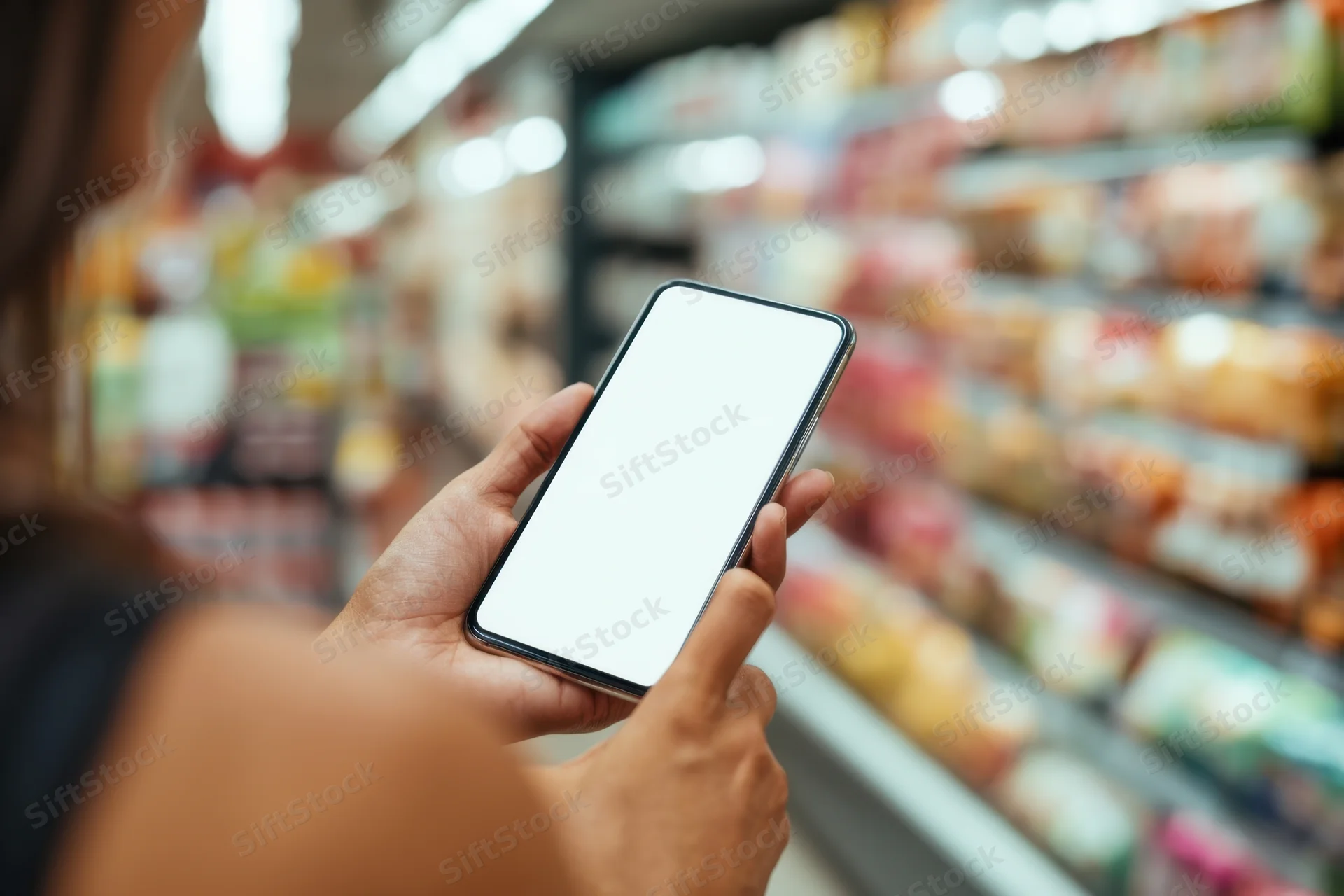 Woman holding smartphone with blank screen in grocery store aisle