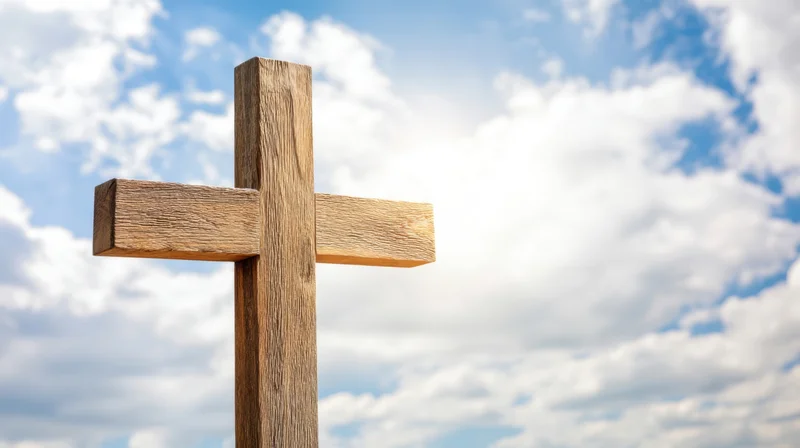 Wooden cross standing against a blue sky with scattered white clouds