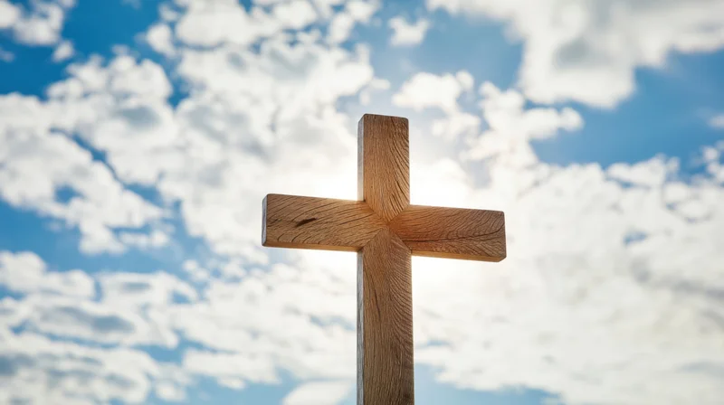 Wooden cross standing against a bright blue sky with scattered white clouds
