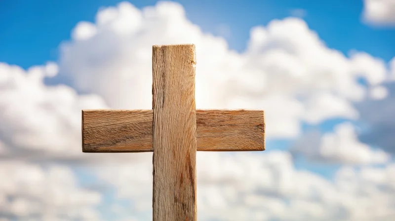 Wooden cross standing against a blue sky with white clouds
