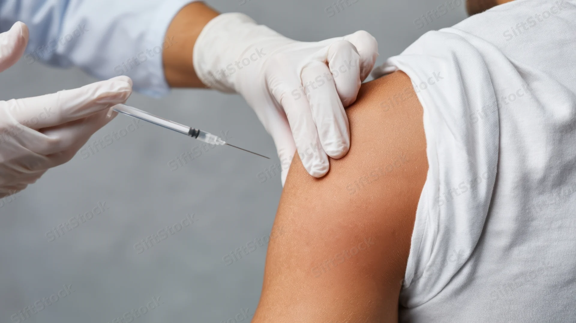 Doctor administering injection into patient's shoulder in clinical setting