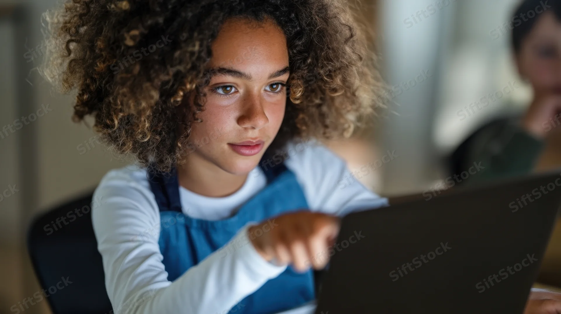 Young girl concentrating on laptop screen in classroom setting