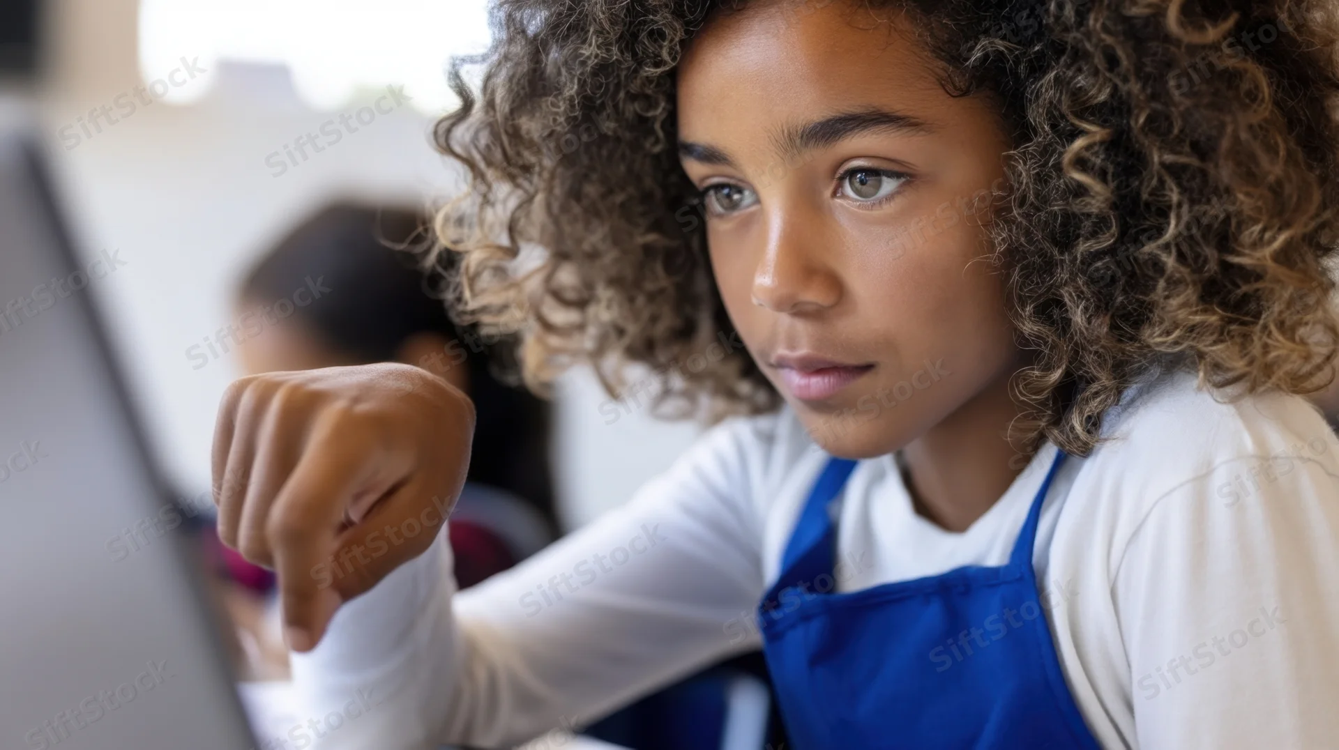 Young girl concentrating on laptop screen in classroom setting