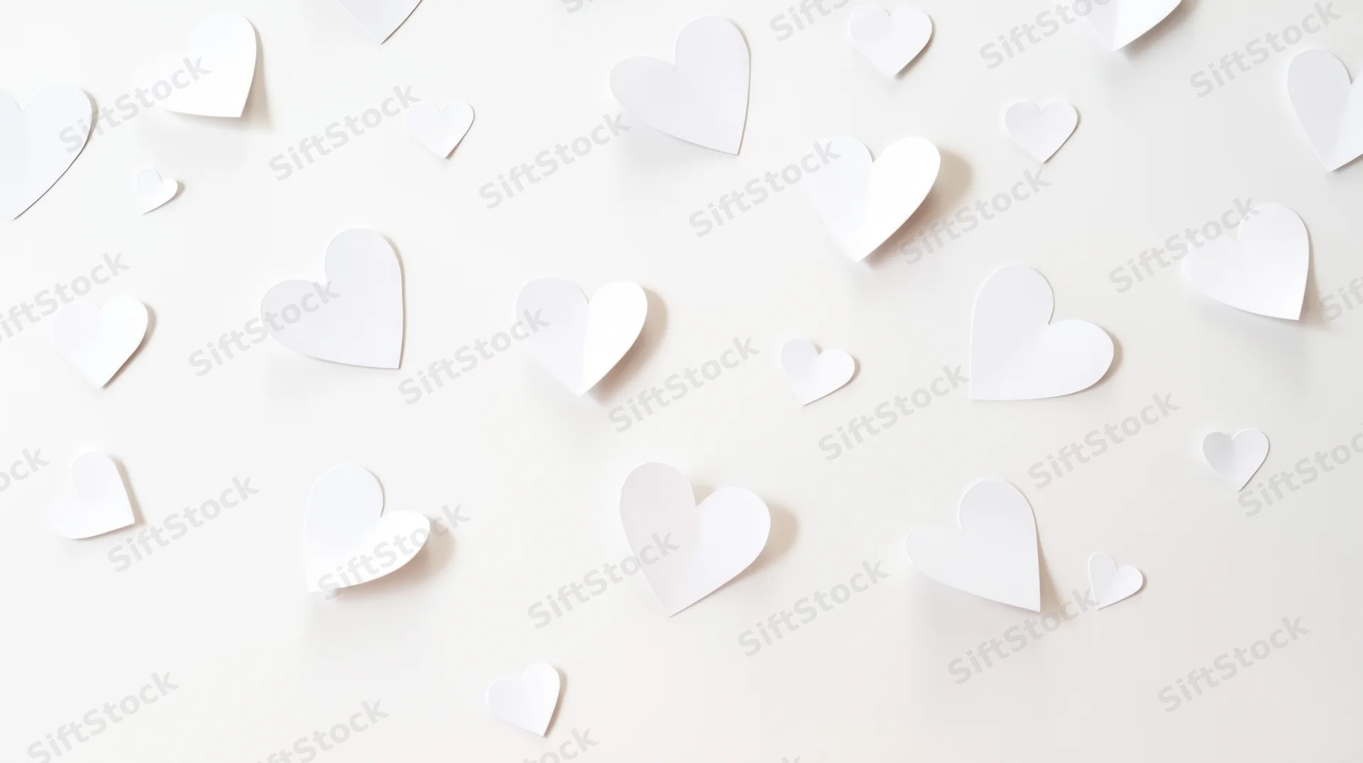 White paper hearts scattered on a light surface in a flat lay arrangement