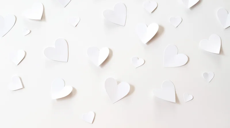 White paper hearts scattered on a light surface in a flat lay arrangement
