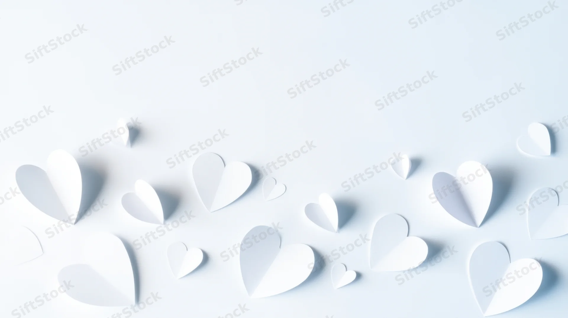 White paper hearts arranged on a light surface with copyspace