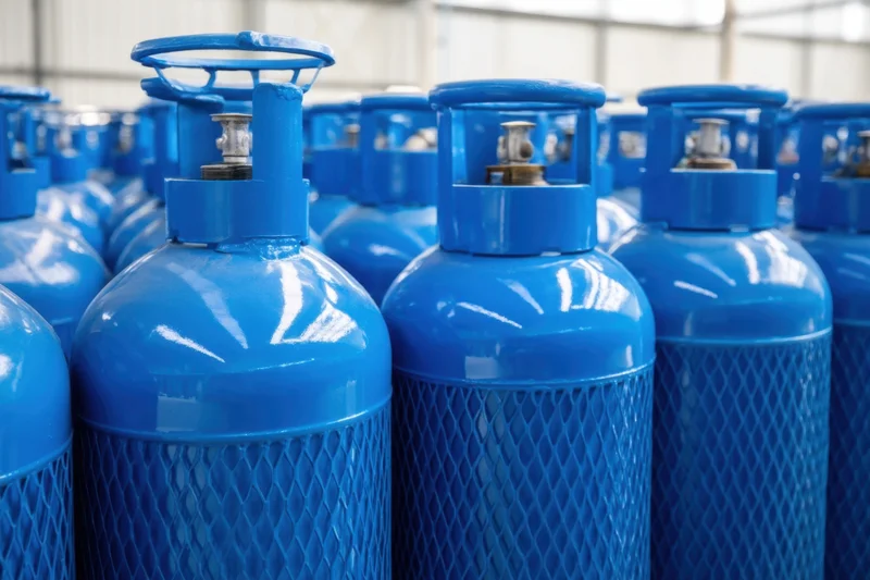 Rows of blue gas cylinders stored in an industrial warehouse