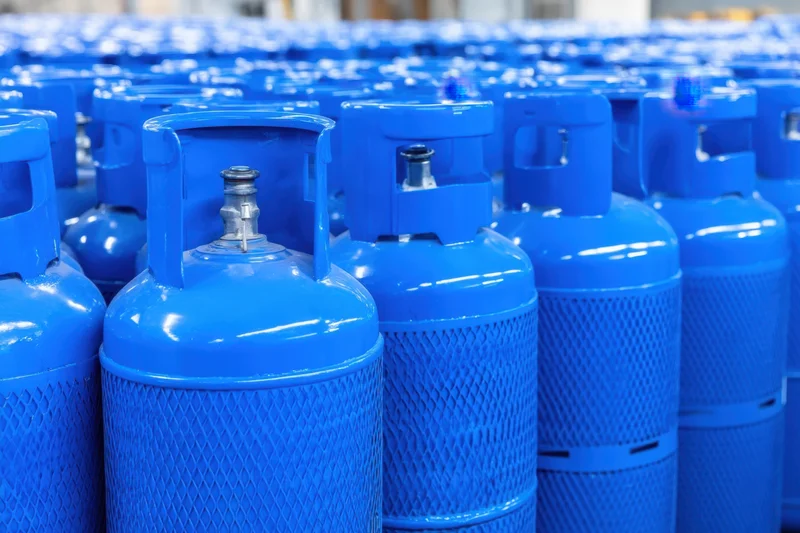 Rows of blue gas cylinders stored in a warehouse facility