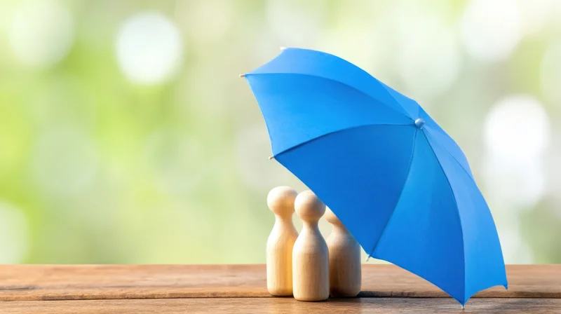 Three wooden figures under a blue umbrella on a wooden table