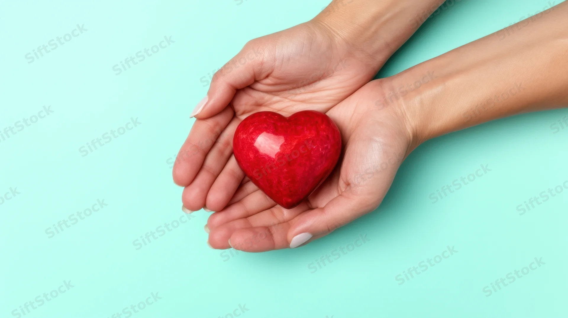 Woman's hands holding a red heart symbol against turquoise background