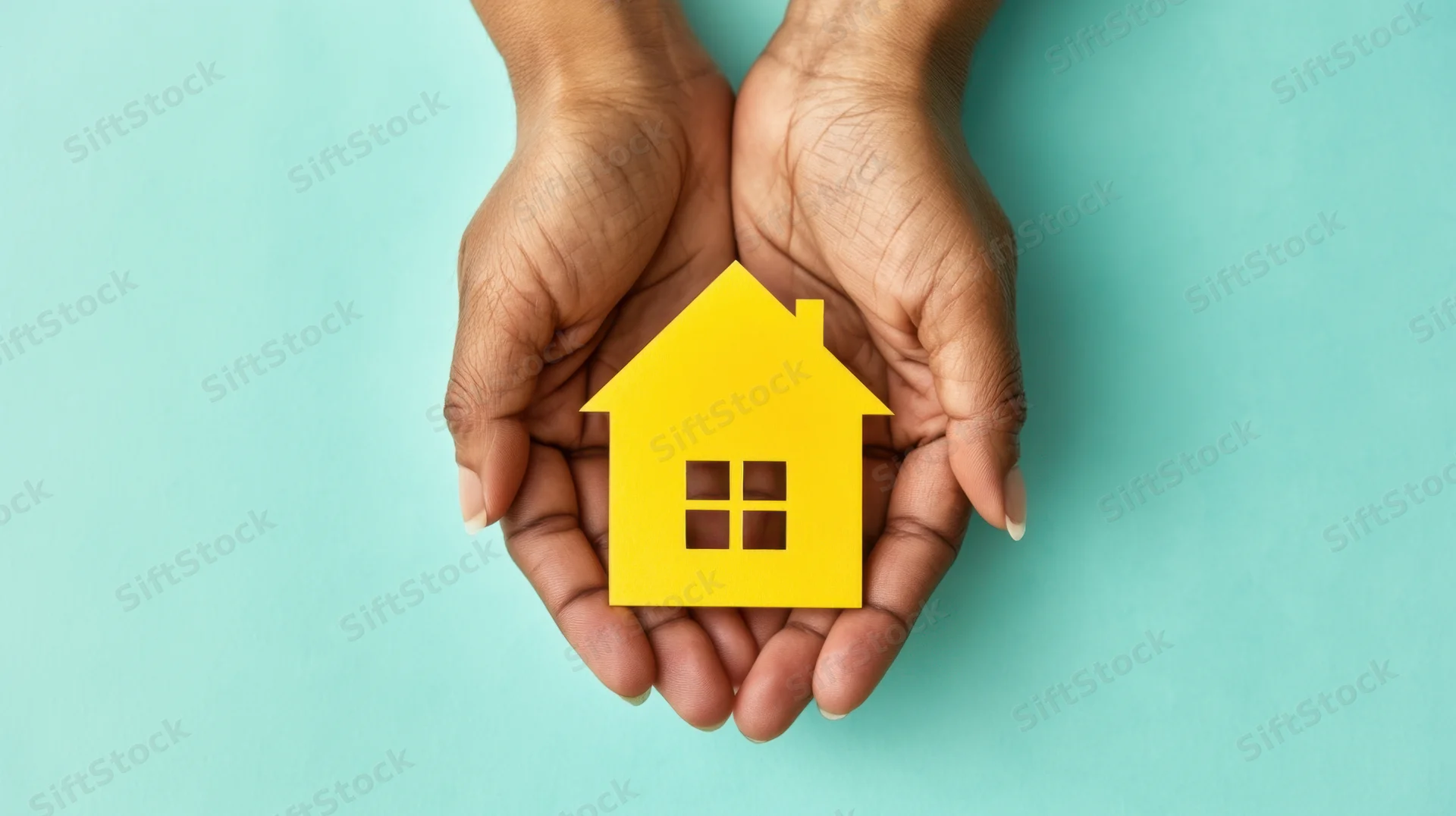 Hands holding a yellow house cutout against a teal background