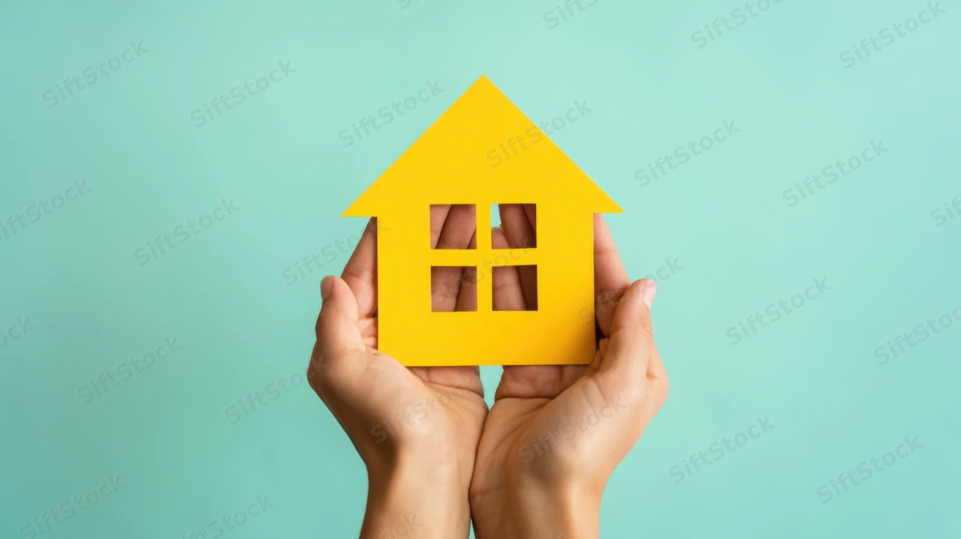 Hands holding a yellow paper house cutout against a teal background
