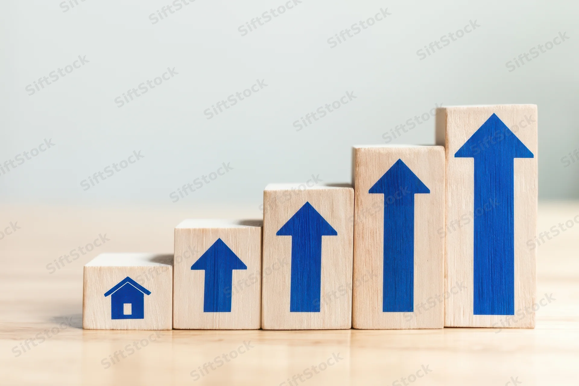 Wooden blocks with blue arrows and house symbol arranged in ascending order on a light surface