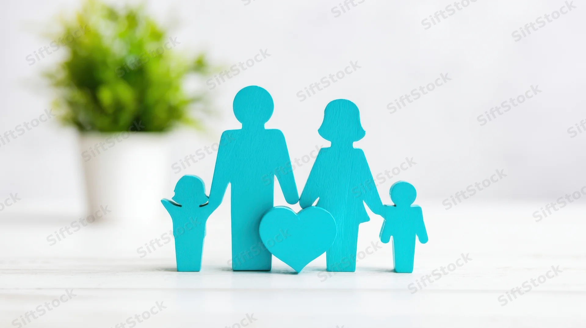 Blue wooden family cutouts with heart symbol on white surface near green plant