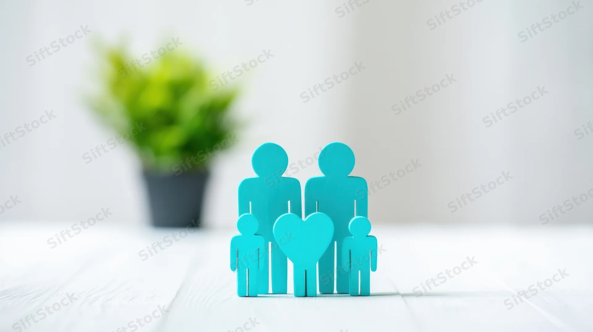 Wooden family cutouts with heart symbol on white table near potted plant