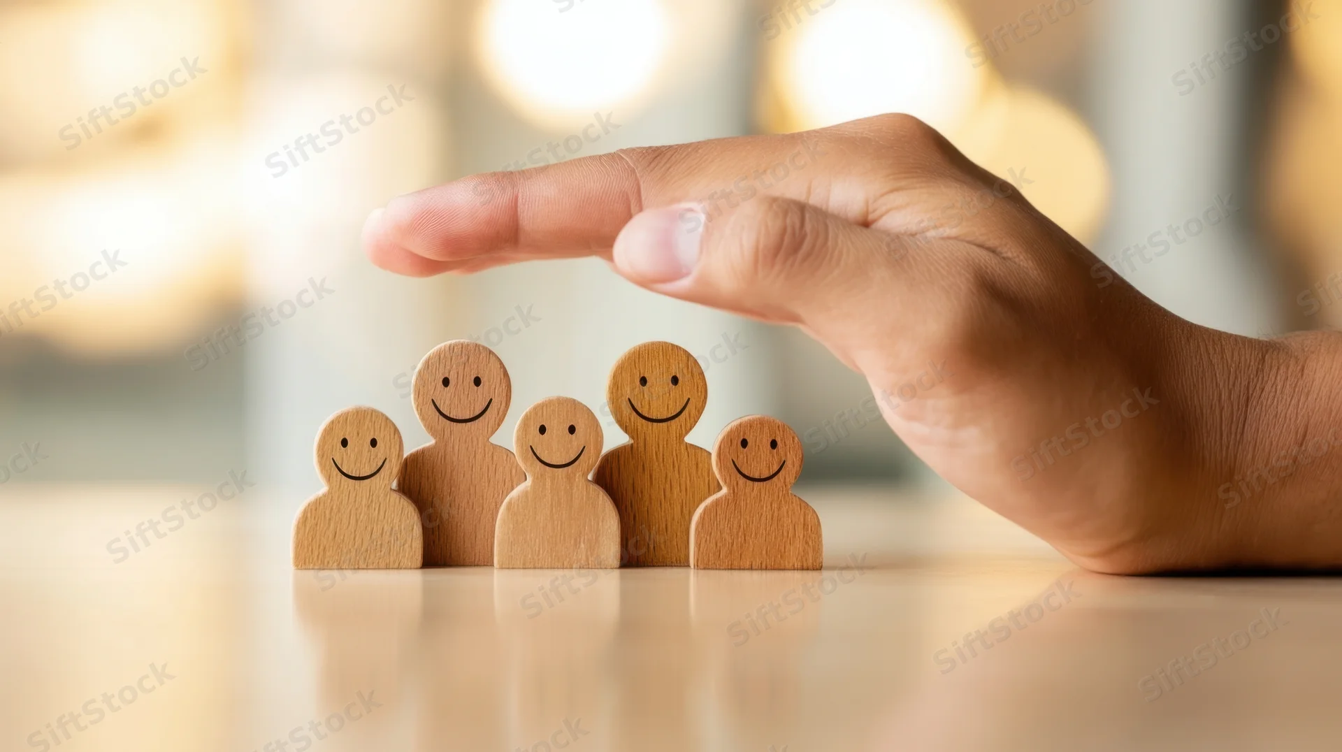 Hand shielding wooden family figurines on a table