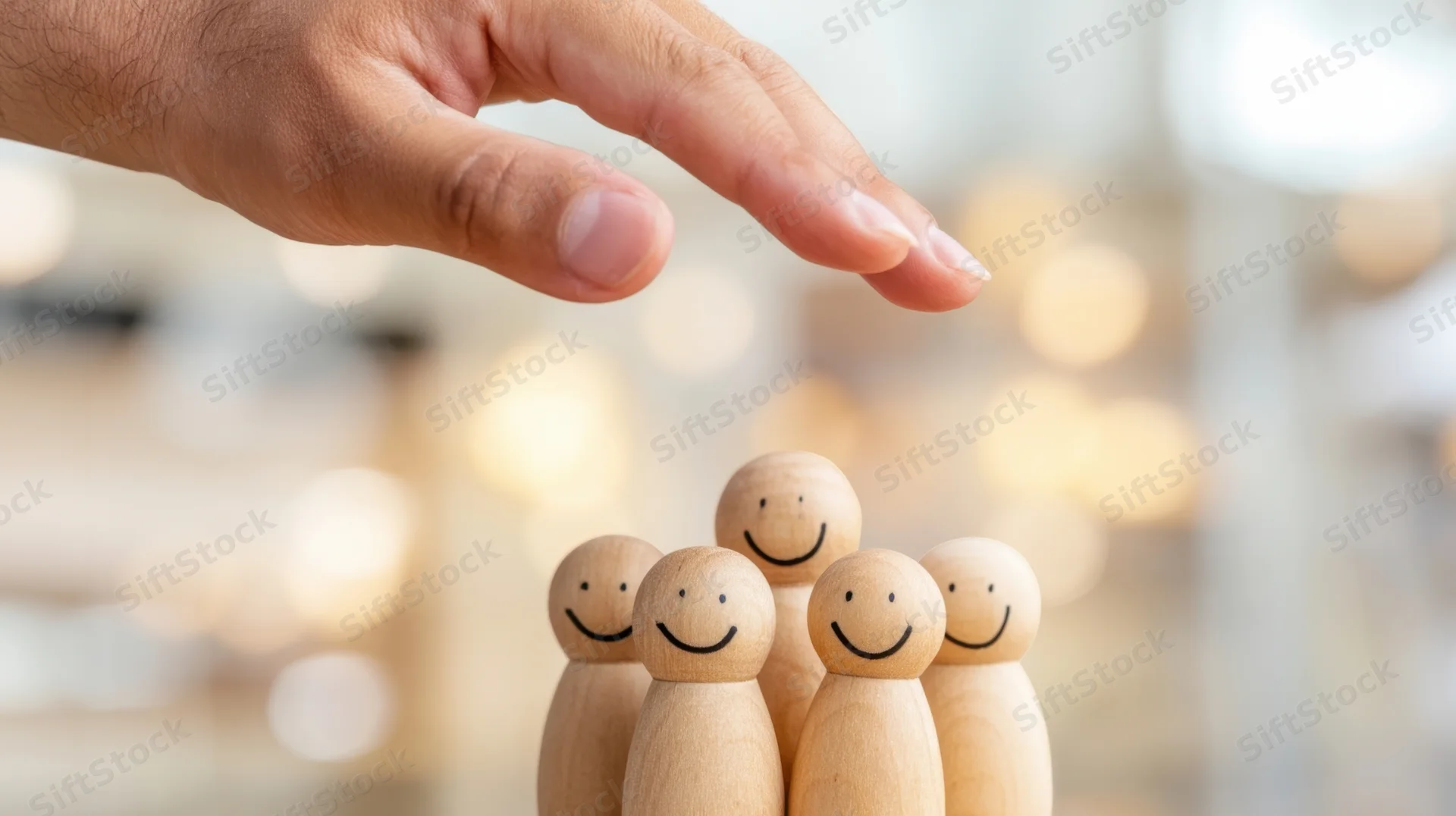 Hand selecting wooden figurines representing a team in an office setting