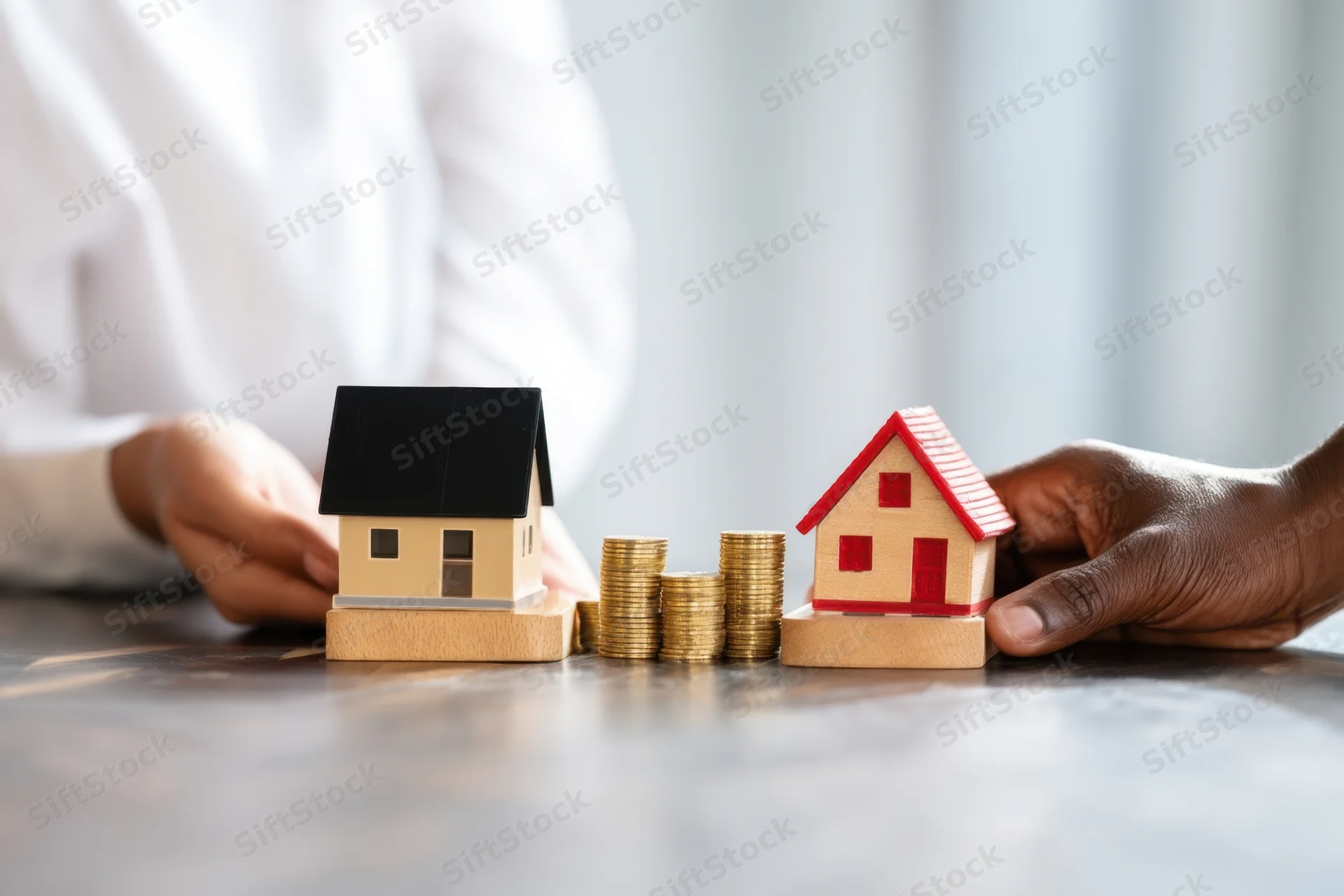 Two people negotiating a real estate deal with model houses and stacks of coins on a table