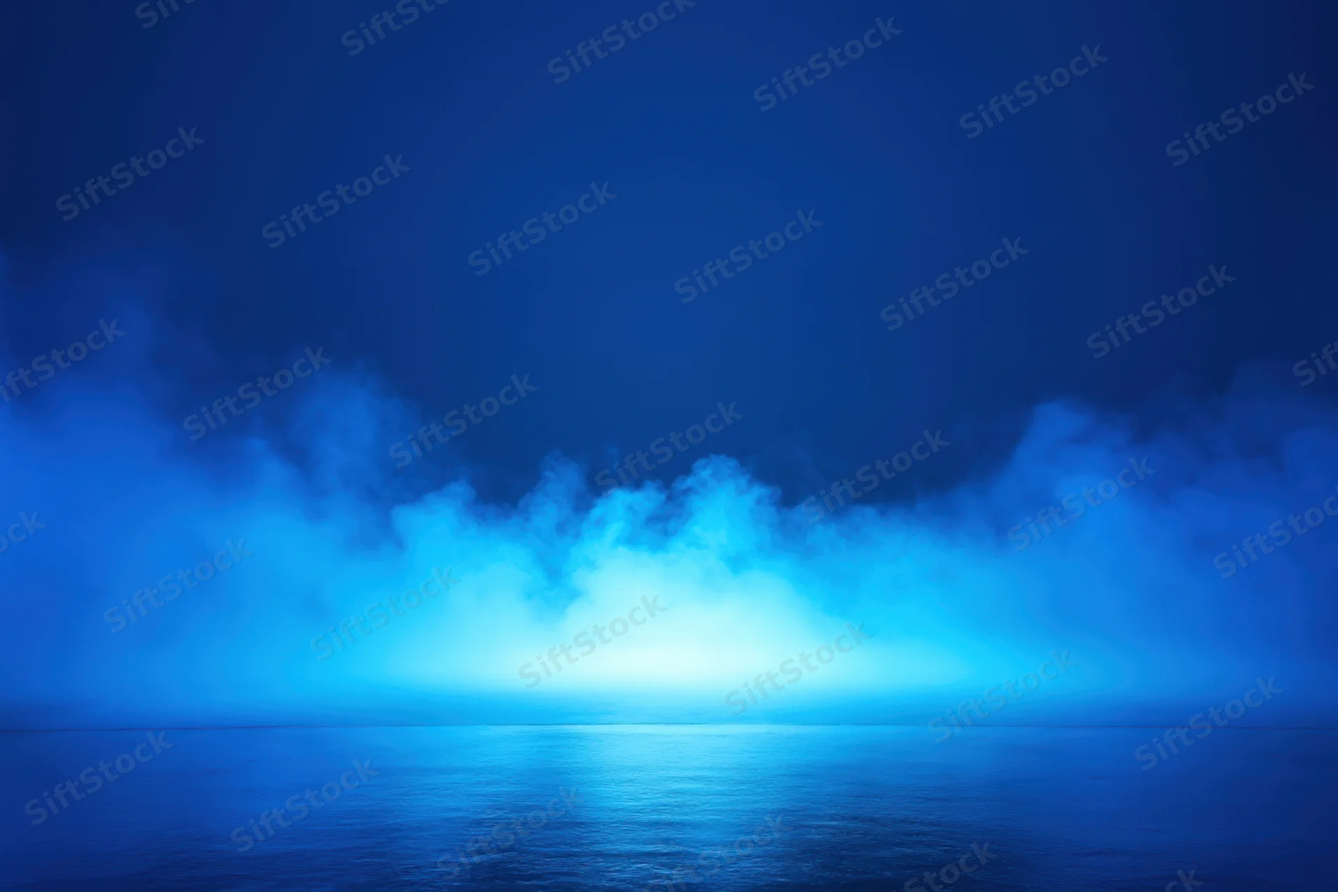 Blue fog over calm water reflecting light at horizon