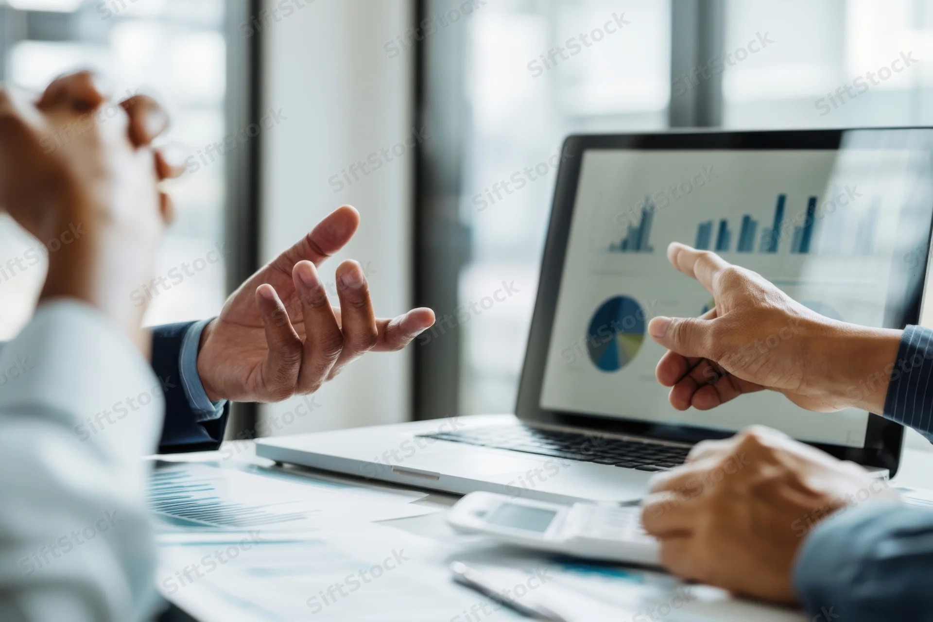 Two professionals discussing data on a laptop during a business meeting in an office