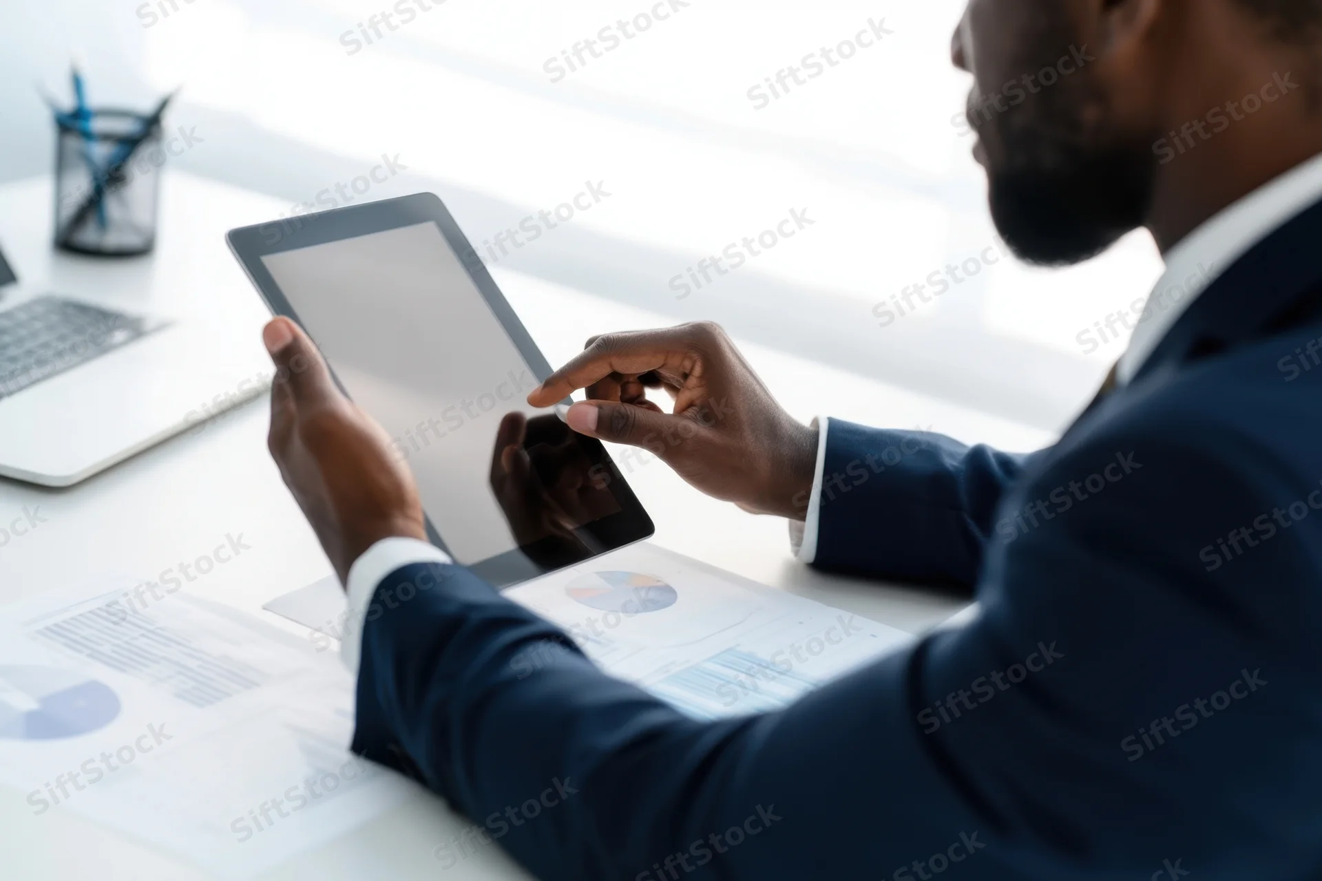 Businessman using tablet with charts on desk in office
