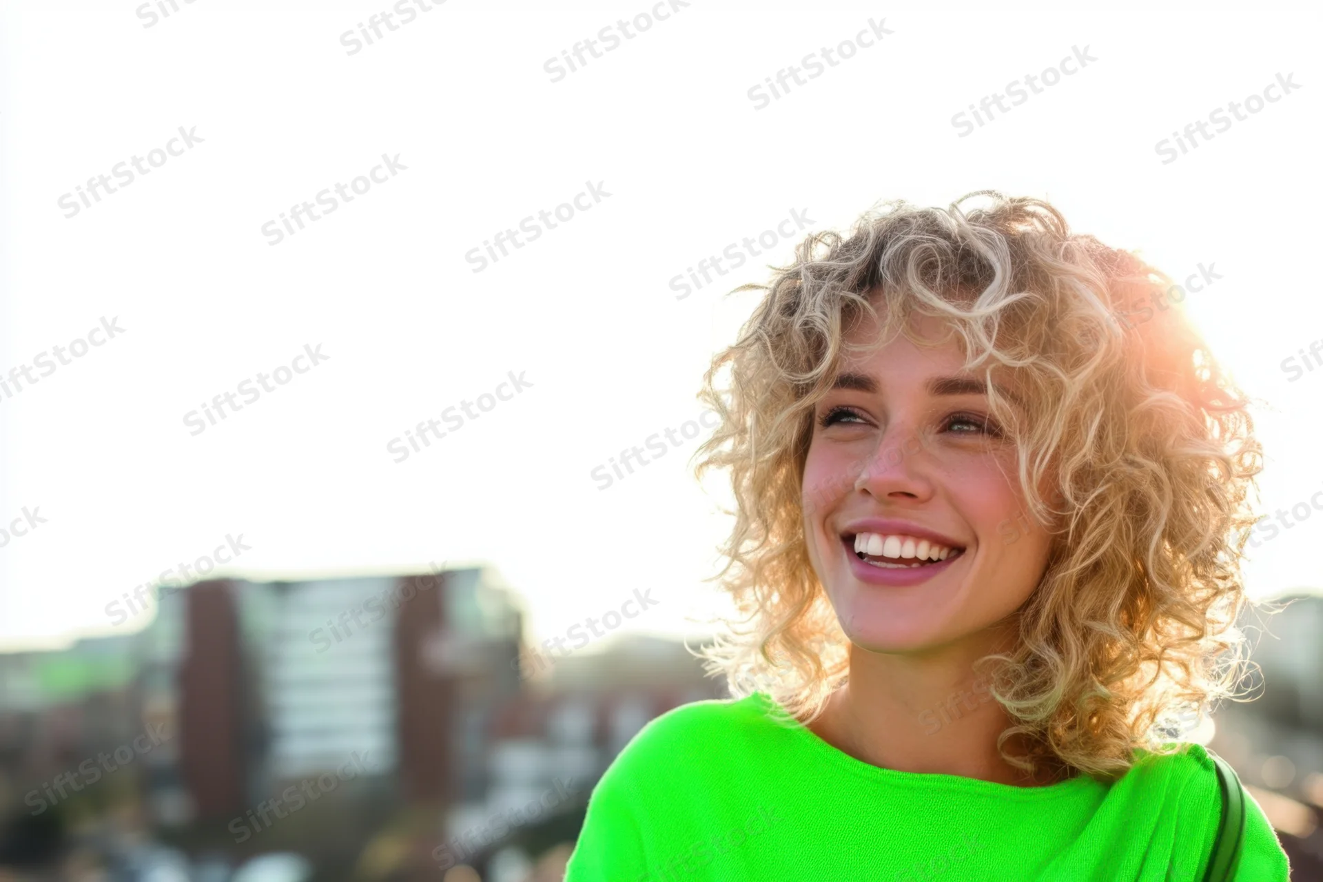 Smiling woman with curly blonde hair in bright green sweater outdoors in city light