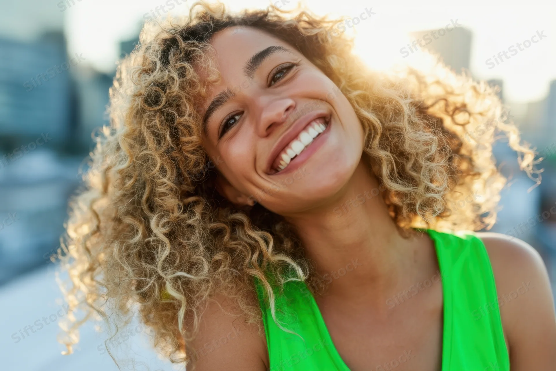 Smiling woman with curly blonde hair in a bright green tank top outdoors in sunlight