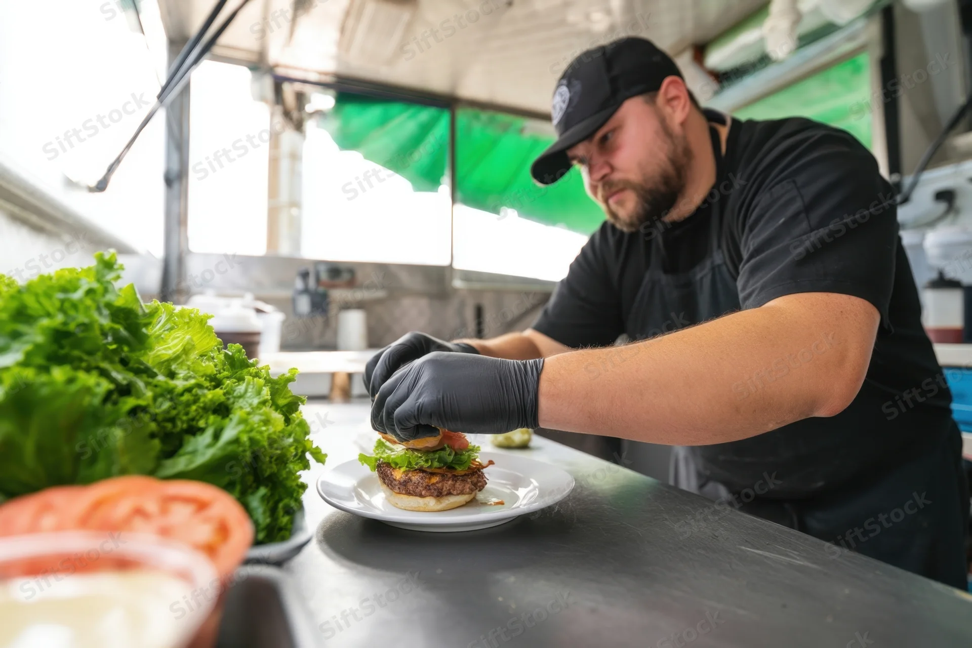 Chef assembling burger on stainless steel counter in food truck kitchen