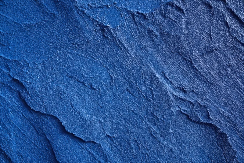 Close-up of a blue textured plaster wall with rough surface and visible cracks