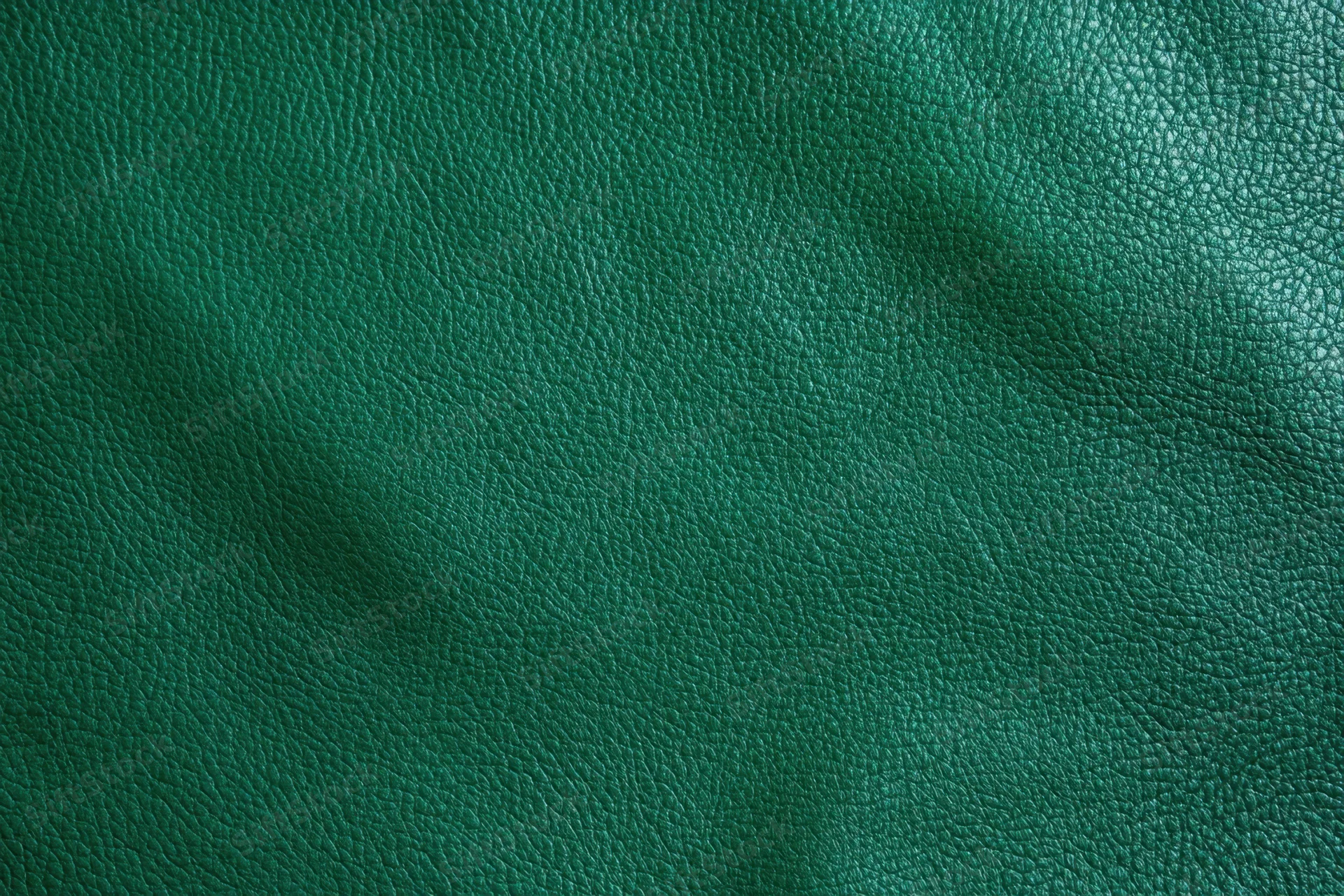 Close-up of dark emerald green leather texture with visible grain and subtle folds