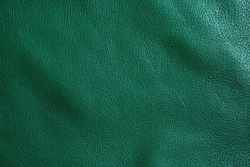 Close-up of dark emerald green leather texture with visible grain and subtle folds