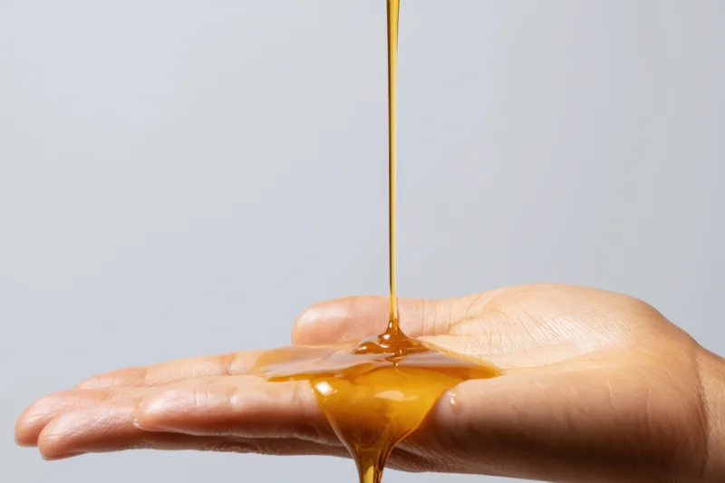 Honey pouring into an open hand against a plain white background