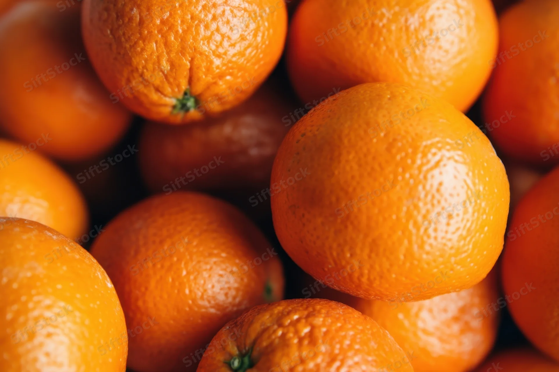 Close-up of a pile of ripe oranges with textured peels and vibrant orange color