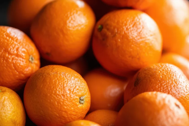 Close-up of a pile of ripe oranges with textured peels and vibrant orange color