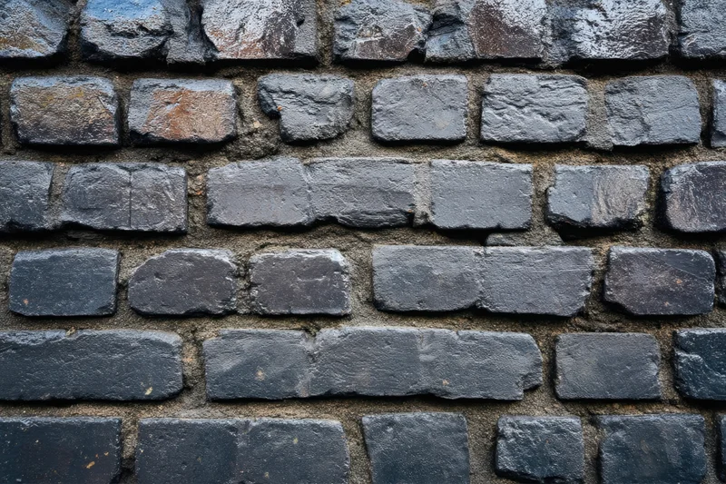 Close-up of dark textured brick wall with irregular stones and mortar joints
