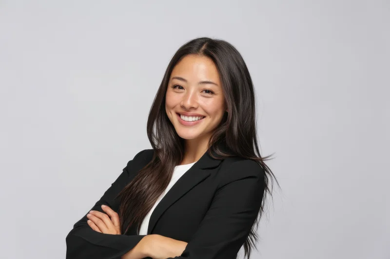 Woman in black blazer smiling with arms crossed against gray background