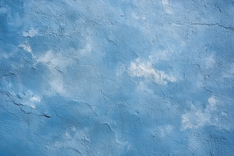Blue textured plaster wall with white patches and cracks