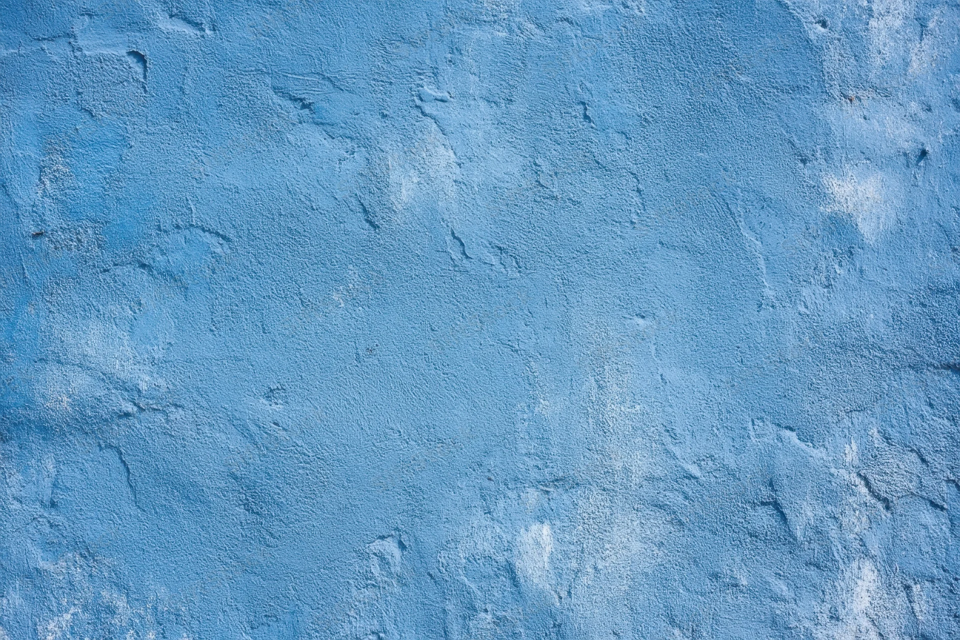 Textured blue plaster wall with rough surface and subtle white patina