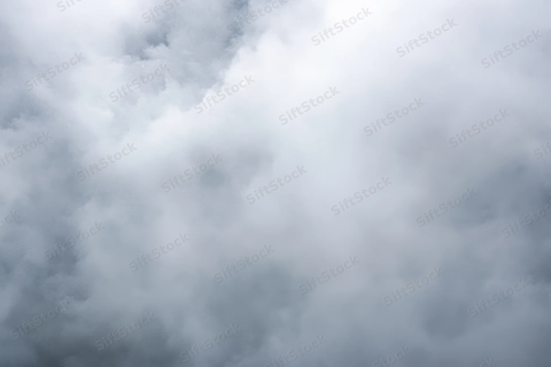 Dense fog swirling across a soft gray sky