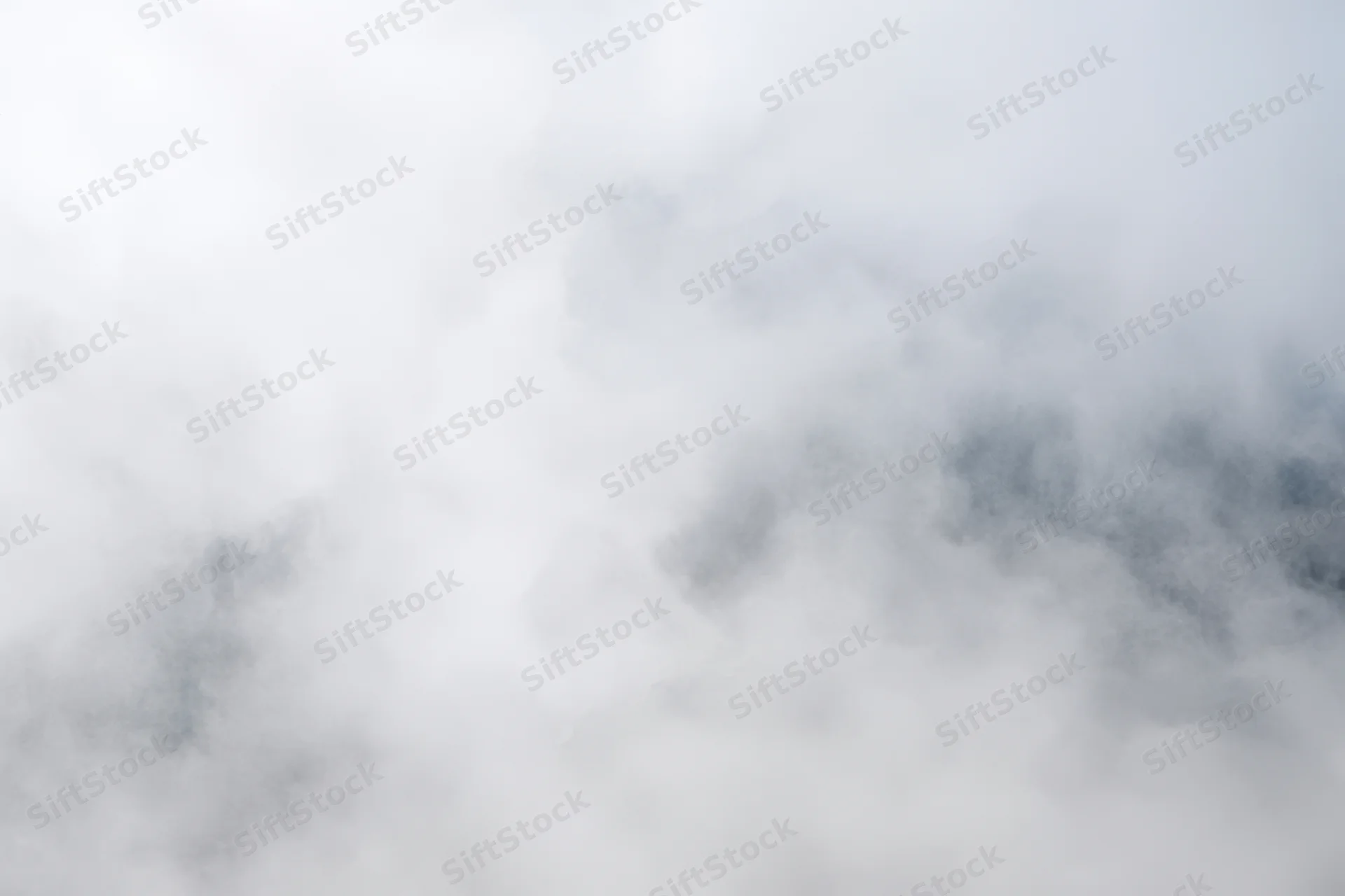 Swirling white fog over a soft gray sky