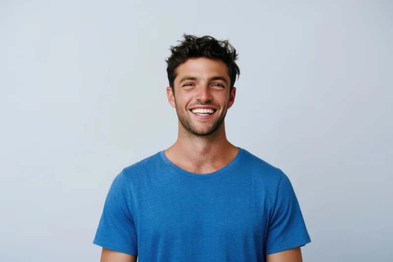 Smiling man in blue tshirt posing against light studio background