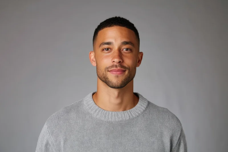 Young man in gray knit sweater smiling at camera in studio setting